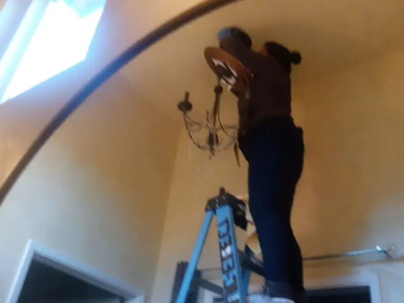 Electrician installing a chandelier in a Attica residence